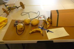 a model of potatos and a banana powering an arduino connected to a machine made from card