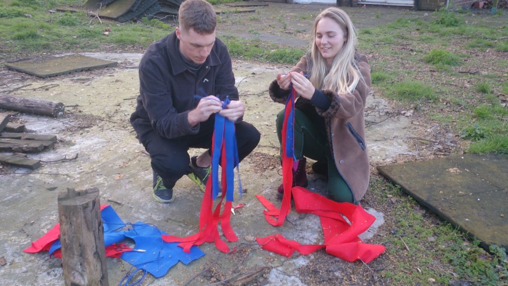 Two participants in workshops plaiting red and blue felt strips