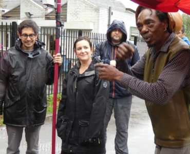 Alex Dayp talking with Rachel Jacobs, Sebastian Gaete holding the weather station pole and Dominic Price - in the rain in Finsbury Park