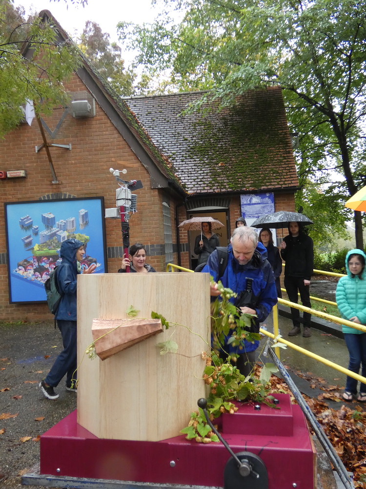 John King decorating the Future Machine with hops outside Furtherfield Gallery in Finsbury Park, Rachel holding the weather station pole in the background