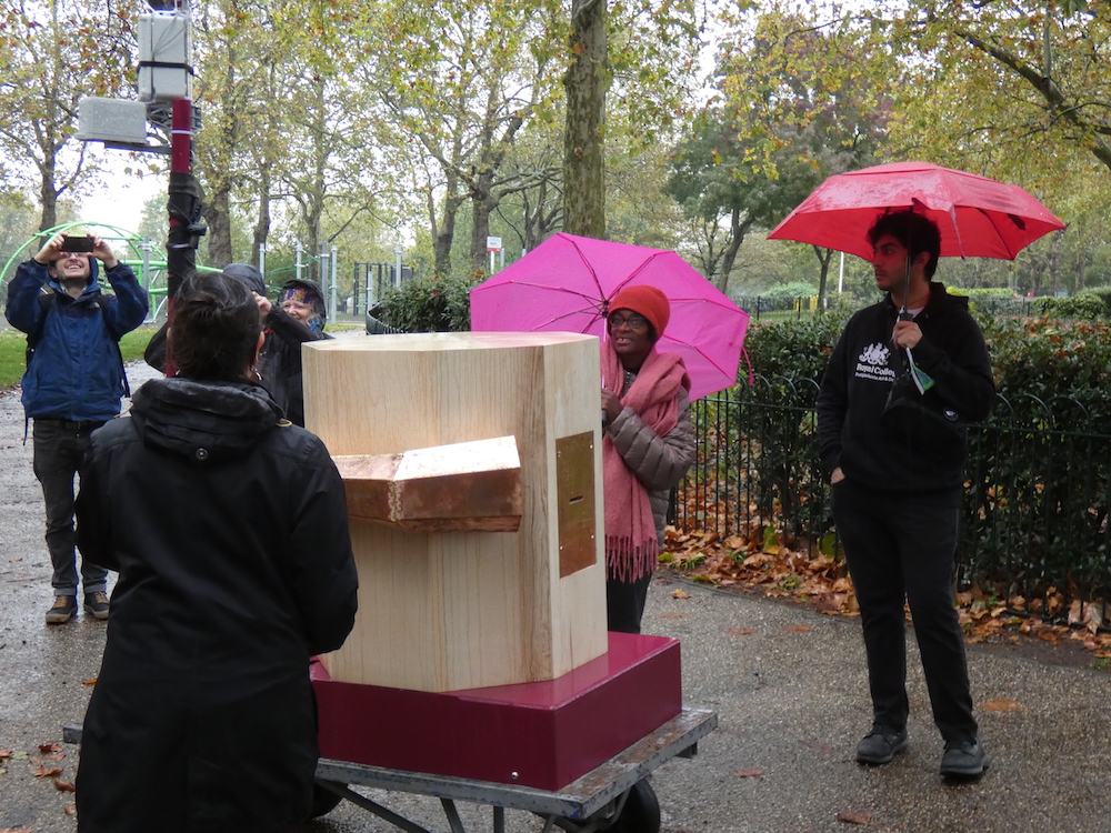 people with umbrellas around the Future Machine in the rain in Finsbury Park