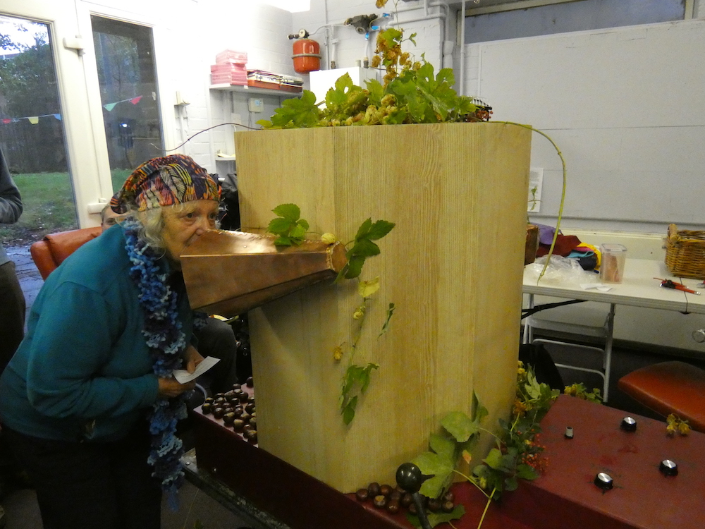 woman in a scarf talking into the copper trumpet hops decorating the machine