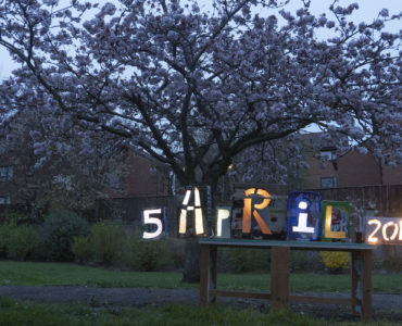 blossom tree in full blossom at dusk, light boxes on a table showing the date 5 April 2019