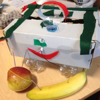 prototype machine made of recycled objects with LED light powered by and apple and a banana