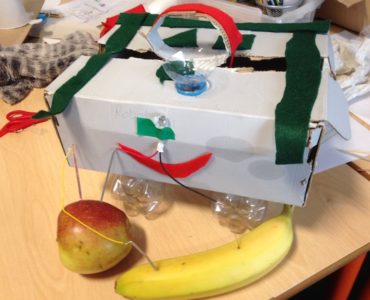 prototype machine made of recycled objects with LED light powered by and apple and a banana