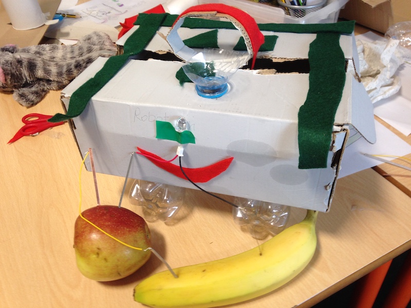 prototype machine made of recycled objects with LED light powered by and apple and a banana