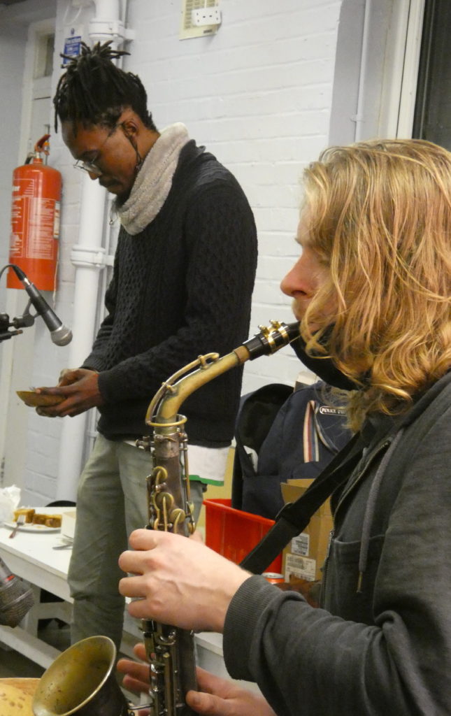 Dave playing the saxophone with Miles behind playing a Mbira