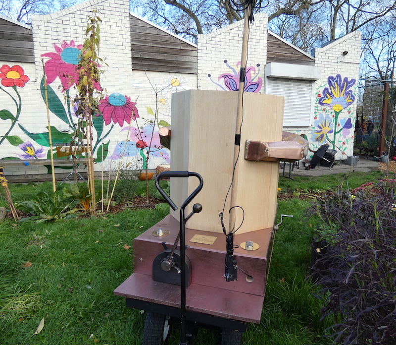 back of the Future Machine in the drumming school garden with the mural behind and the lever and weather pole