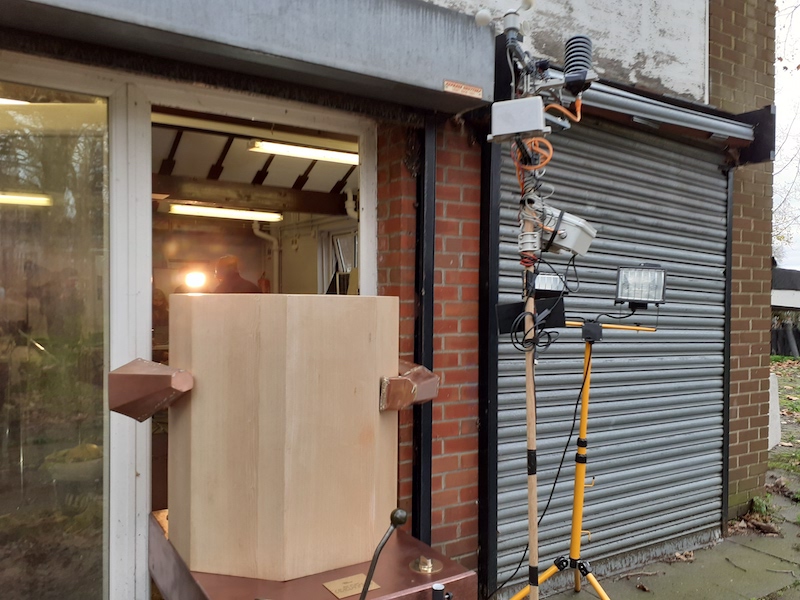 The Future Machine from behind in the doorway of Furtherfield Commons in Finsbury Park, with the weather station pole and lights next to it.