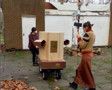 Rachel pulling the Fuutre Machine outside Furtherfield Commons with Indira in front holding the weather station on a pole