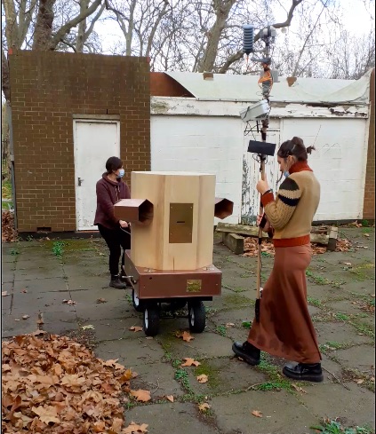 Rachel pulling the Fuutre Machine outside Furtherfield Commons with Indira in front holding the weather station on a pole