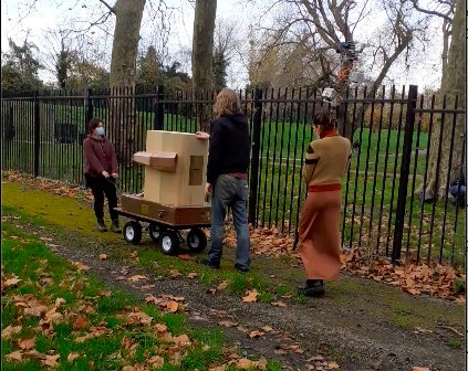 Rachel Jacobs and Dave Kemp pulling the Future Machine up hill in Finsbury Park, Indira Lemouchi is holding the weather station and walking behind