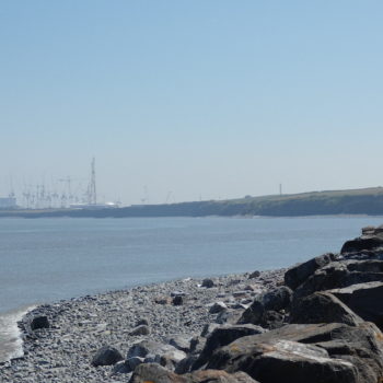 Caroline walking along the coastal path at Kilve with the sea on the left and Hickley Point C nuclear power station in the distance