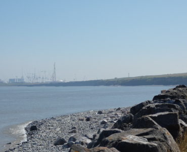 Caroline walking along the coastal path at Kilve with the sea on the left and Hickley Point C nuclear power station in the distance