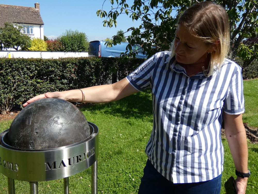 Caroline in Jubilee Gardens with her metal sculptural memorial to her Dad - Maurice Locke. A globe depicting the village of Cannington.