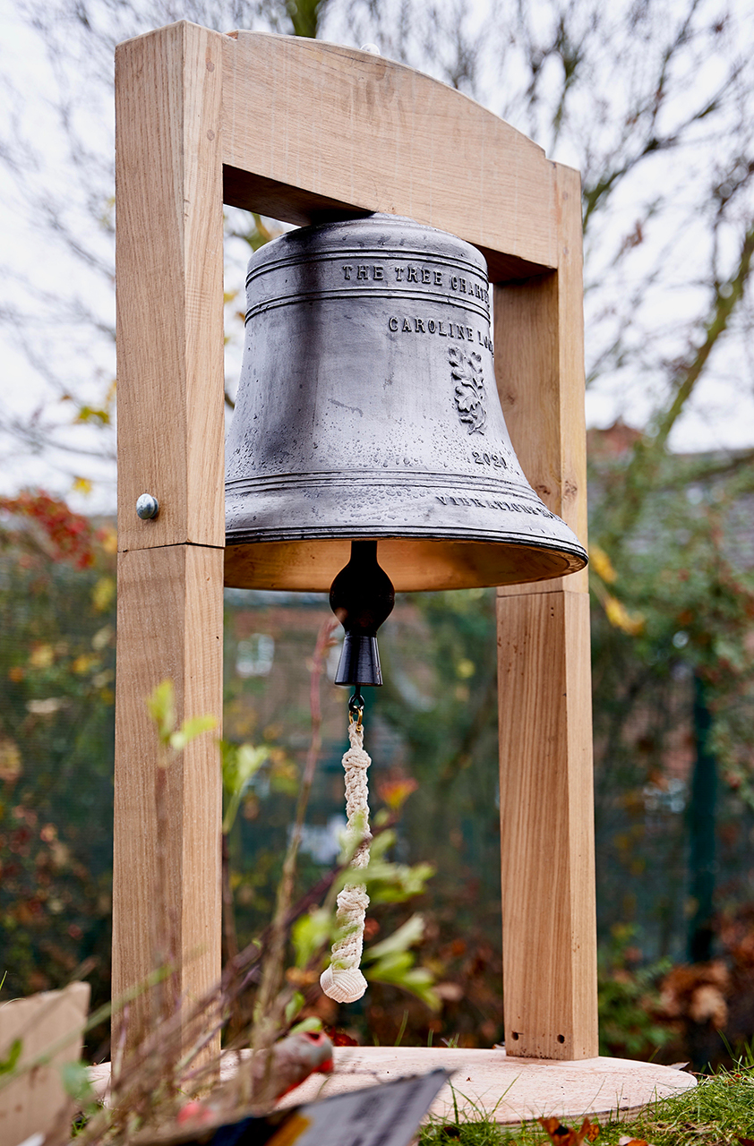 Caroline Locke's tree charter bell on a wooden frame with trees in the background