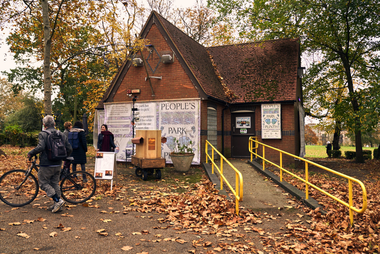 The Future Machine, a man with a bike, two women talking to the artist Rachel Jacobs in front of Furtherfield Gallery, surrounded by Autumn trees