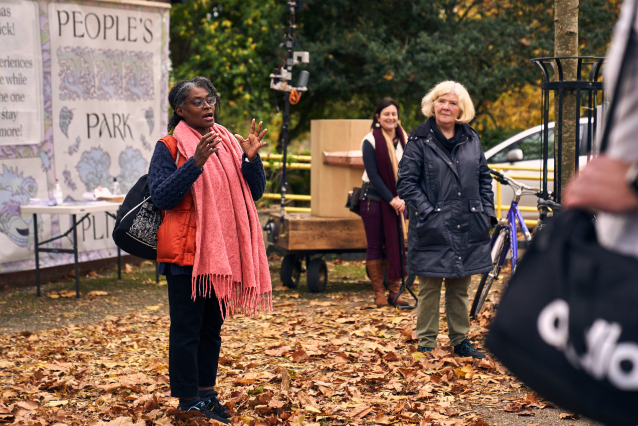 Esi Eshun talking with her hands up, Jo Roach listening, Rachel Jacobs standing in front of Future Machine in the background with trees and Furtherfield Gallery behind