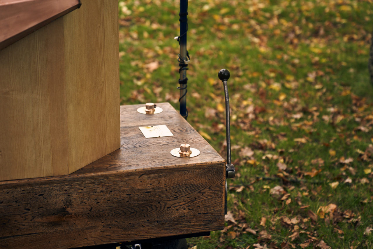 the back of Future Machine, with the lever, pole, brass dials and sign, grass and leaves