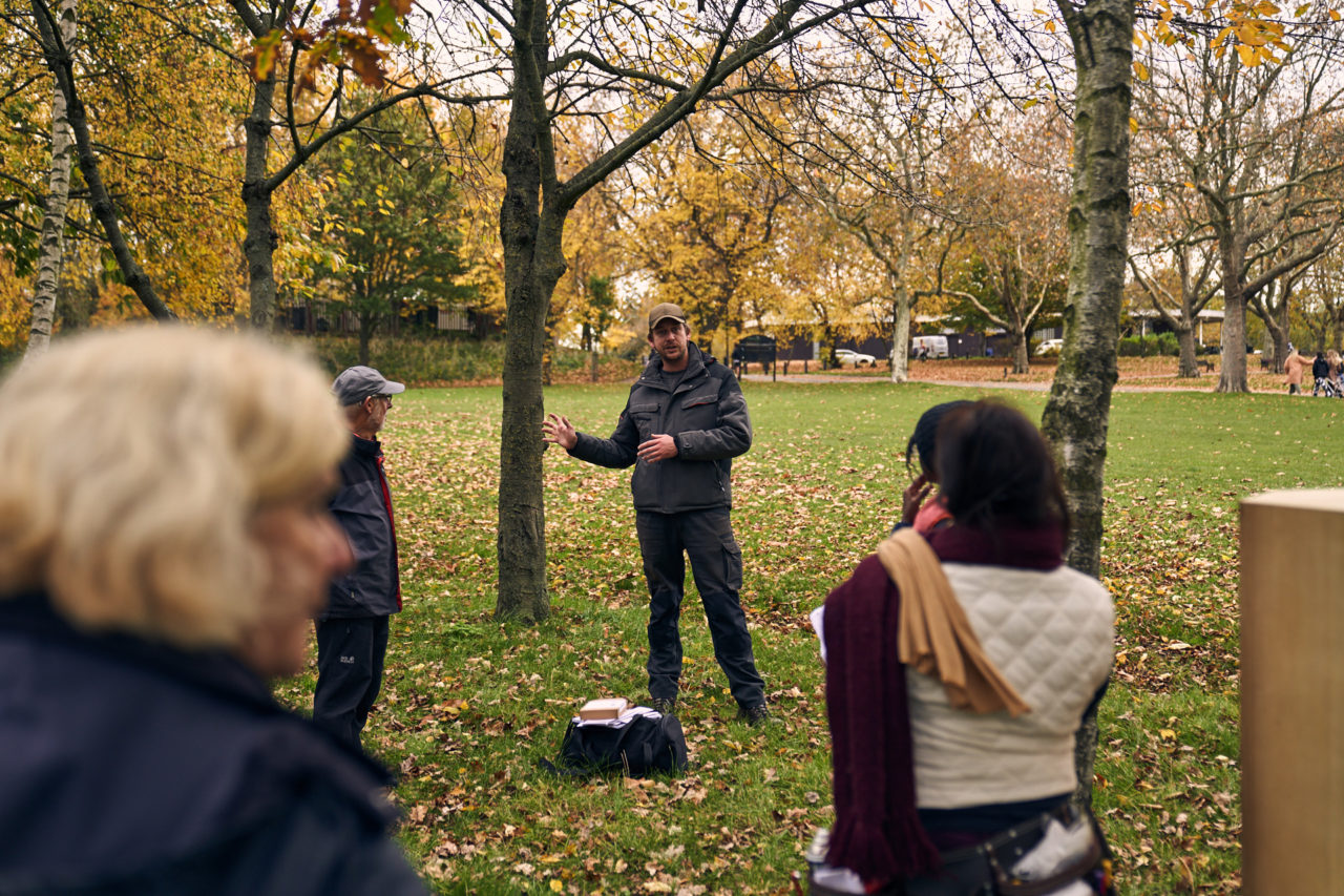 Ricard the park ranger talking amongst the silver birch with people standing around listening