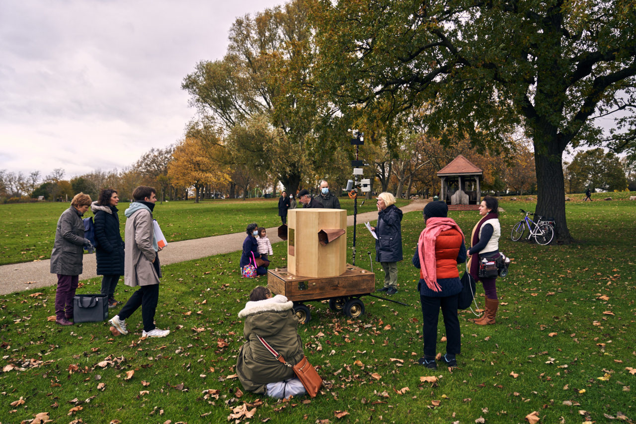 Jo Roach reading a poem with the Future Machine and people around it