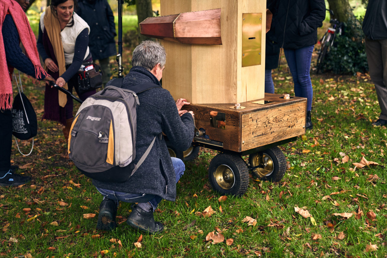 a man turning the handing on the Future Machine, leaves, grass and people's legs