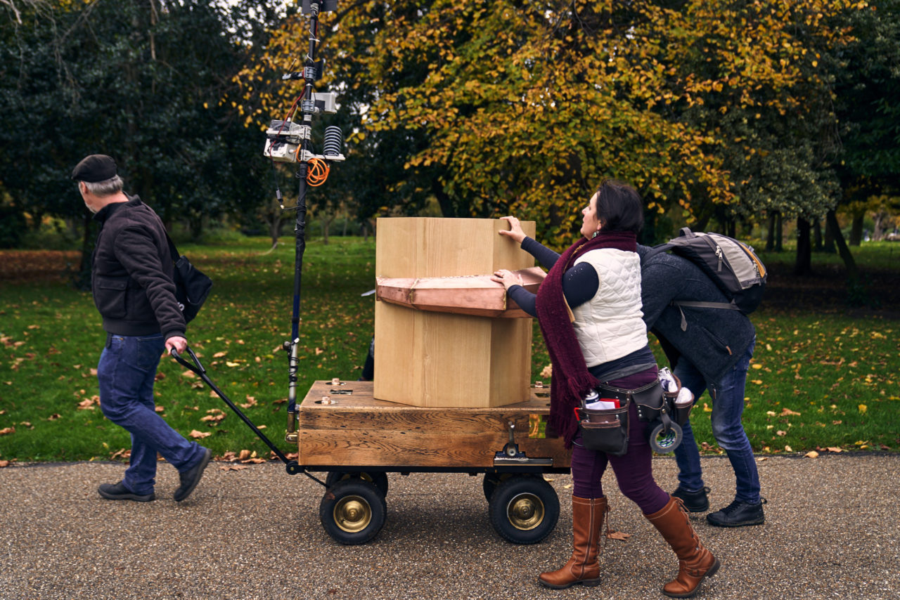 A man pulling the Future Machine and Rachel and another man pushing with autumnal trees in the background