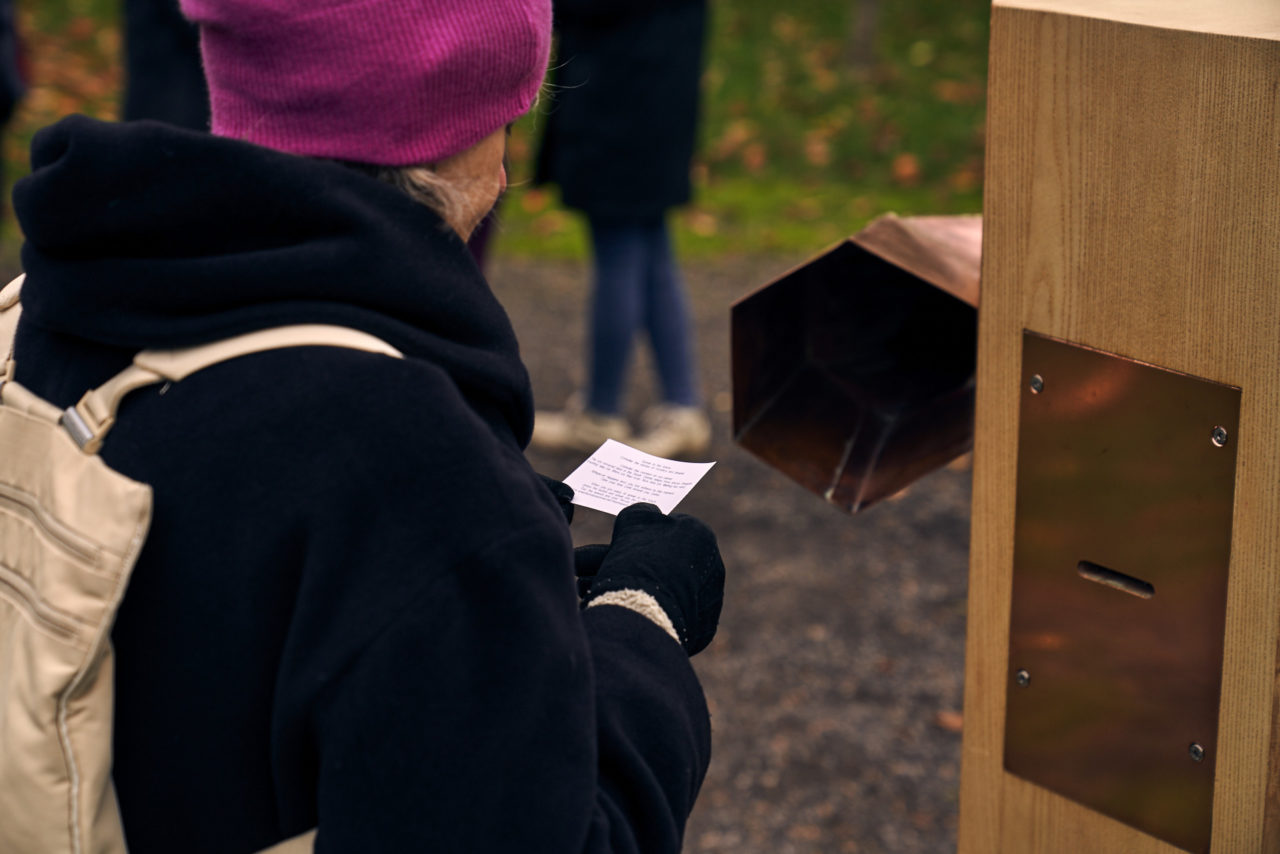 A woman in a pink hat reading her future quest next to the Future Machine