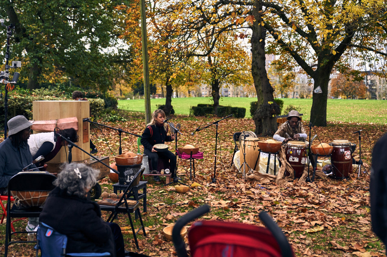Miles, Rachel, Future Machine Terese singing, Alex drumming, people sitting watching, autumn leaves and trees