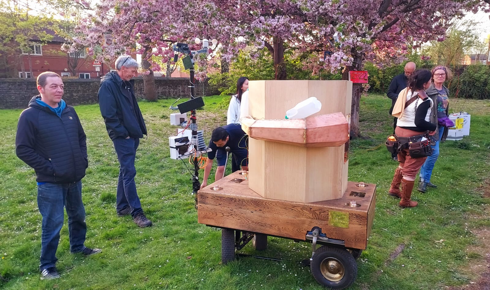 Future Machine with people standing around, blossom trees in the back ground