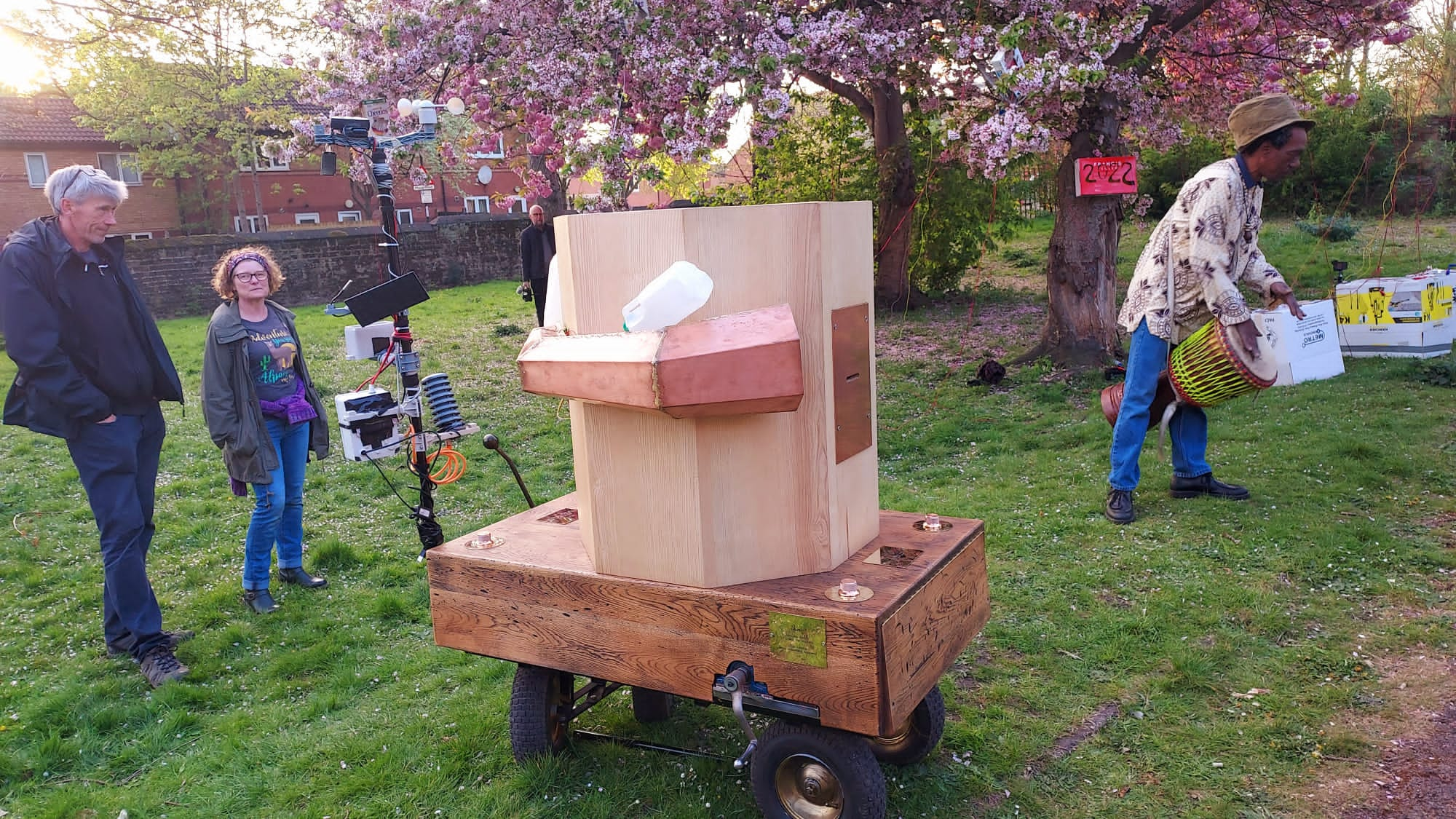 Future Machine with people standing around, blossom trees in the back ground