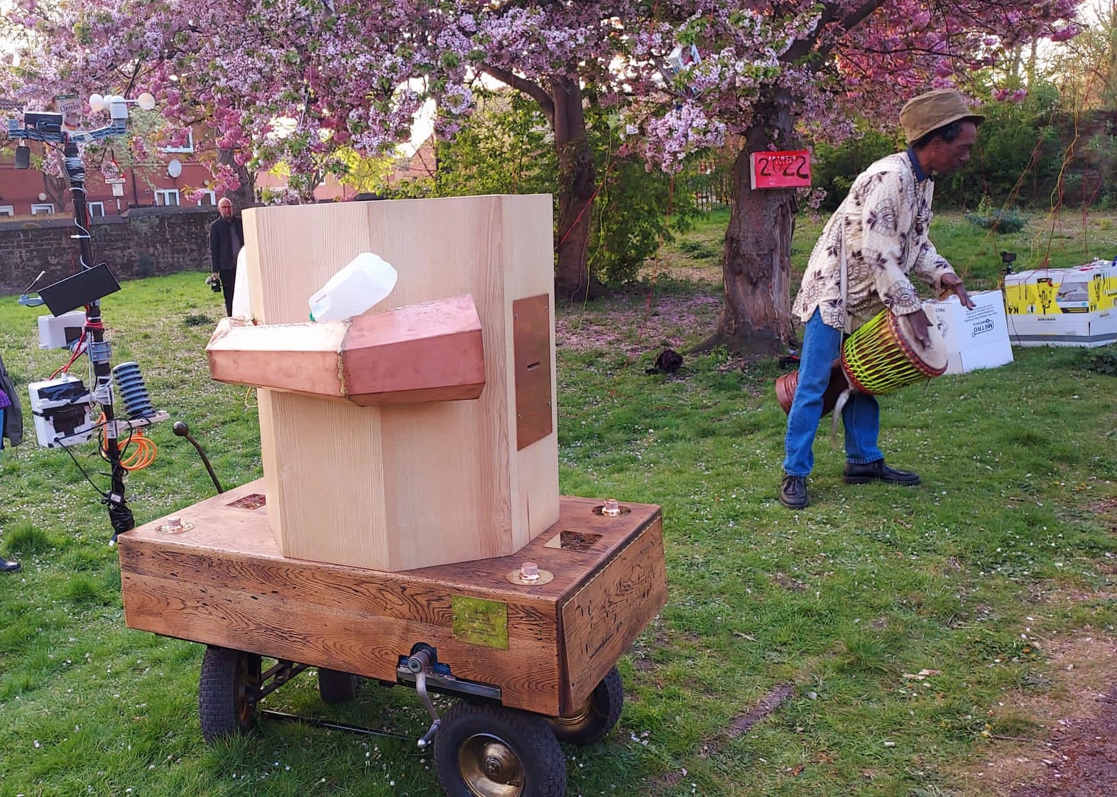 Future Machine in the foreground, Alex playing the djembe drum and the blossom trees with the red sign with 2022. Roger in the distance with his camera