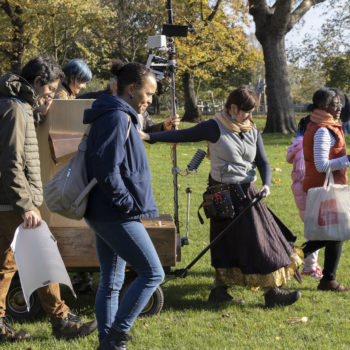 Future Machine being pulled by it's artist companion alongside a procession of five people. Autumn trees in the background.