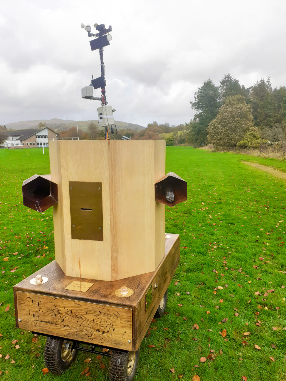 Future Machine with the weather station at the back, fells in the distance, trees and grass