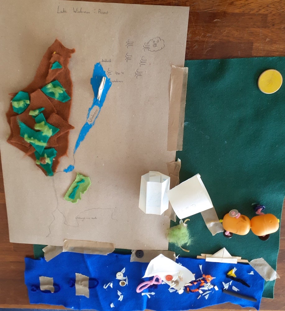 A data map made of felt and plastic and paper with a lake, a plastic car and bits of rubbish