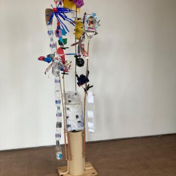 Sculpture of plants and creatures made of rubbish in a small cardboard stand.