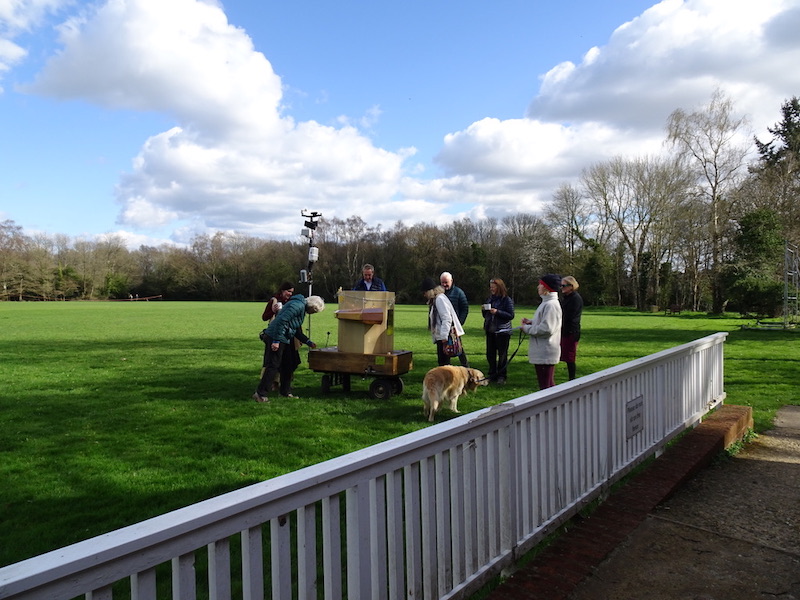 Future Machine and people gathered around on the cricket ground, with blue sky and fluffy clouds above