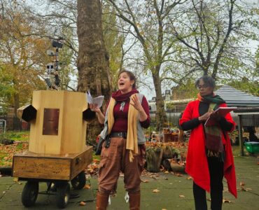 Rachel talking next to Esi watching with Future Machine and trees behind them
