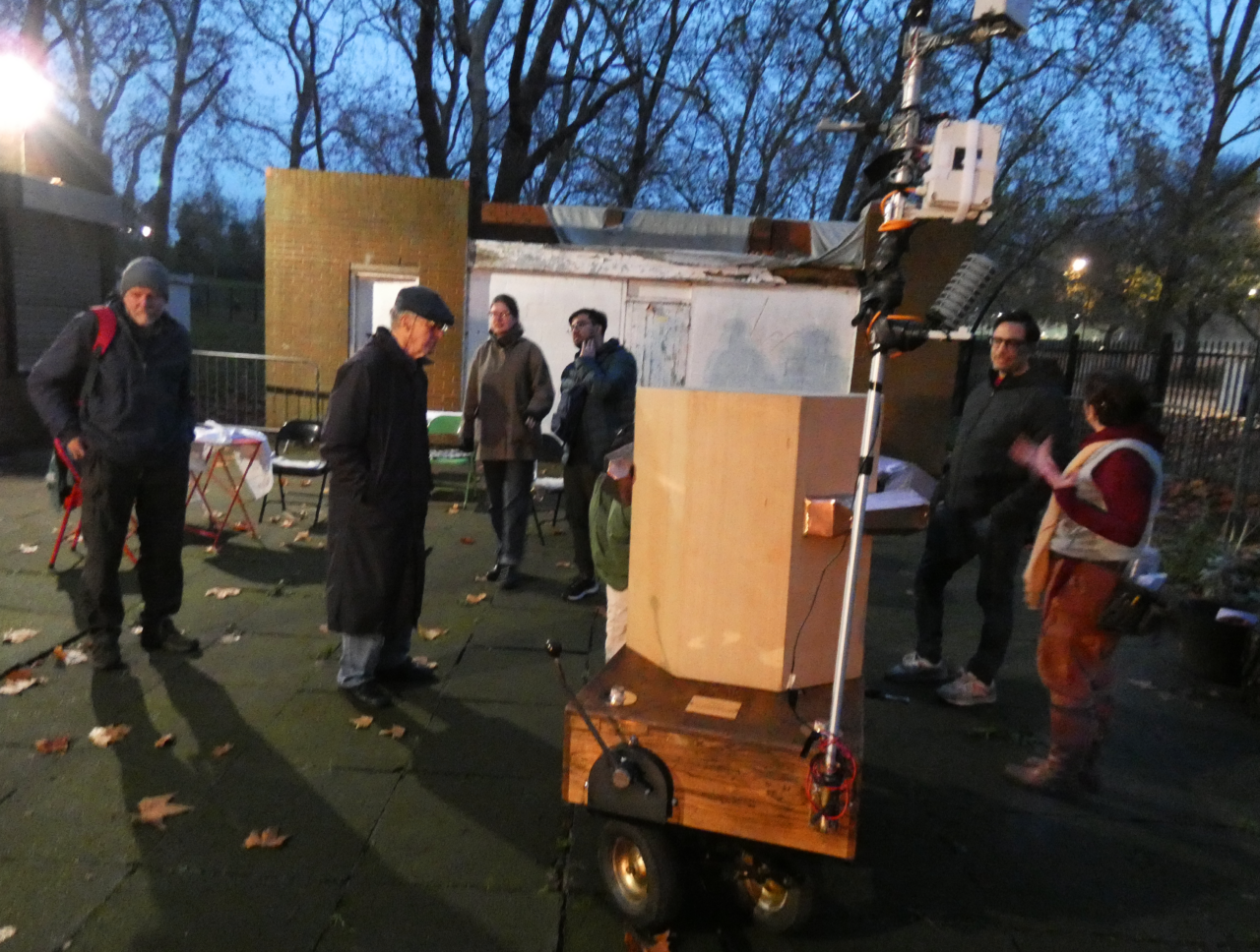 People standing arund Future Machine, at dusk
