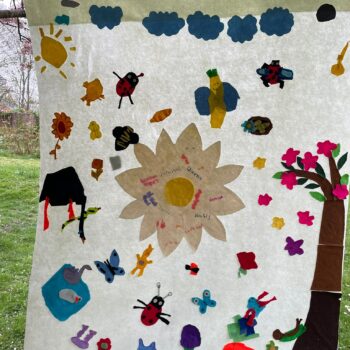 a large banner with insects, clouds, flowers and a blossom tree made from coloured felt