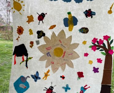 a large banner with insects, clouds, flowers and a blossom tree made from coloured felt