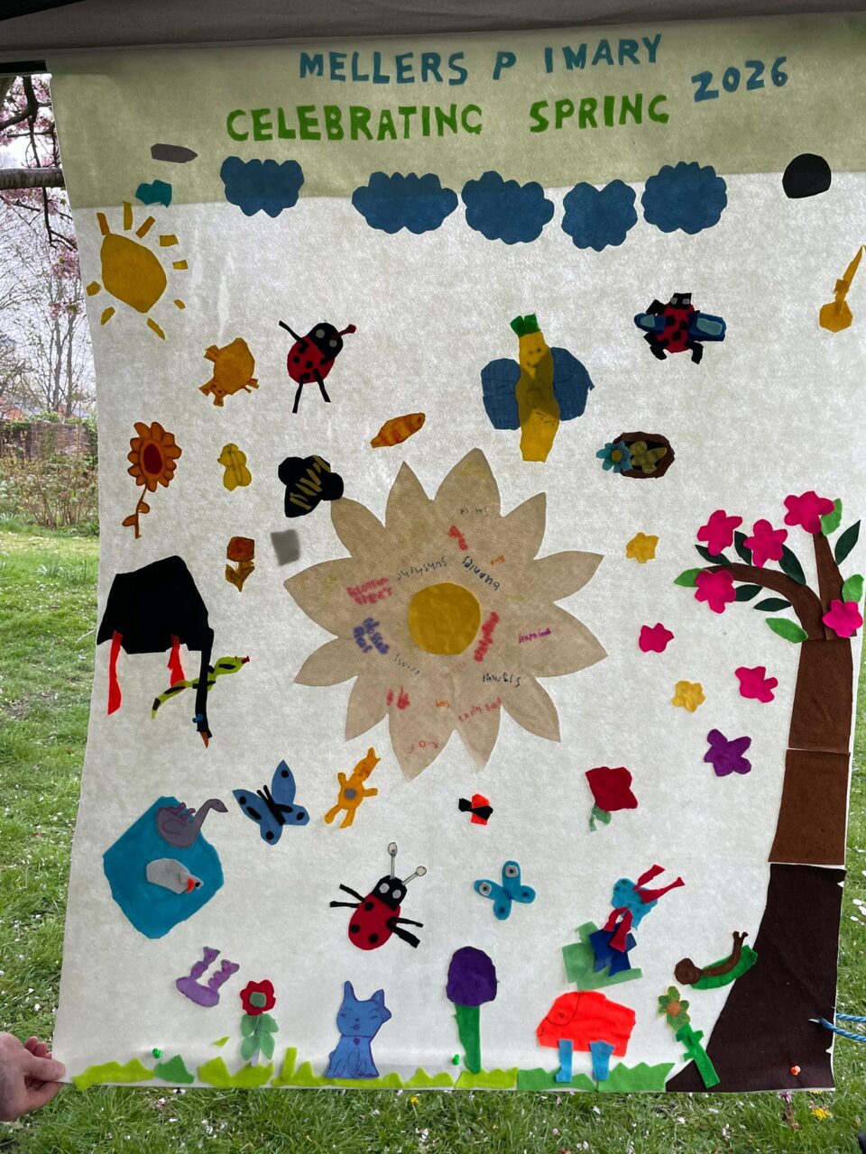 a large banner with insects, clouds, flowers and a blossom tree made from coloured felt