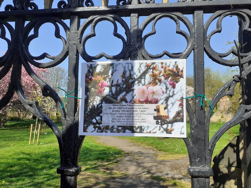a sign about the Future Machine event with an image of blossoms tied to a iron gate with blossoms in the background