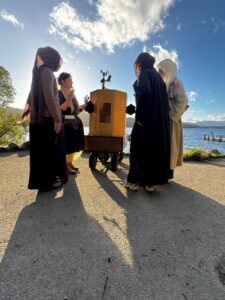 Future Machine with Lake Windermere behind, a low sun, Future Machine's companion and 3 people with around them
